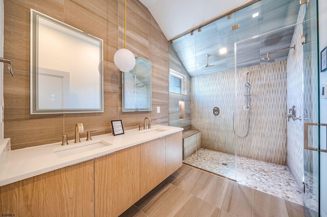 full bathroom with tile walls, lofted ceiling, a sink, tiled shower, and tile patterned floors