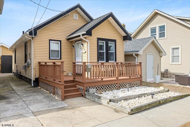 view of front facade featuring a deck and roof with shingles