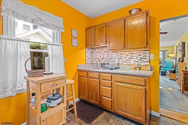 kitchen featuring light countertops, backsplash, a sink, and brown cabinetry