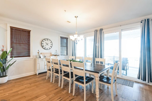 dining room featuring light wood-type flooring, baseboards, ornamental molding, and a chandelier