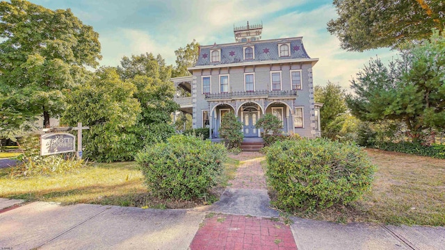 second empire-style home with covered porch, a high end roof, and mansard roof