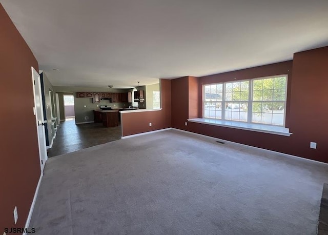 unfurnished living room with visible vents, baseboards, and dark colored carpet