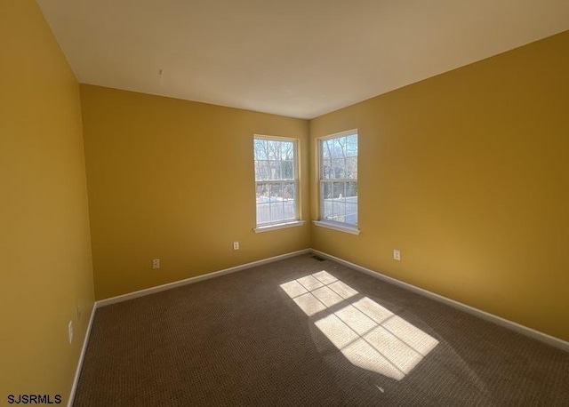 empty room with dark colored carpet and baseboards