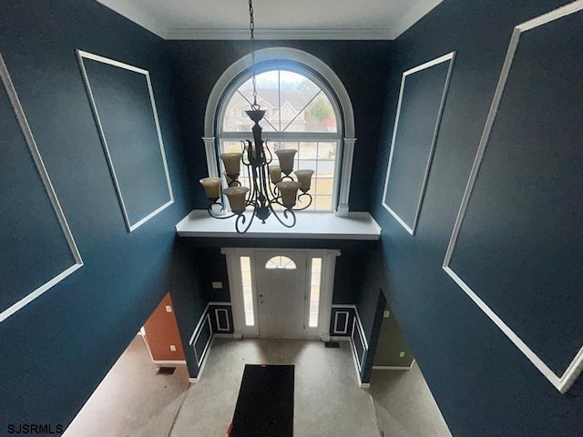 foyer featuring crown molding, a towering ceiling, visible vents, and an inviting chandelier