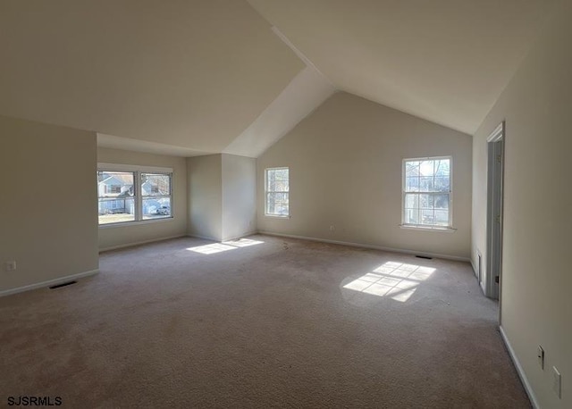 carpeted spare room with baseboards, visible vents, and vaulted ceiling