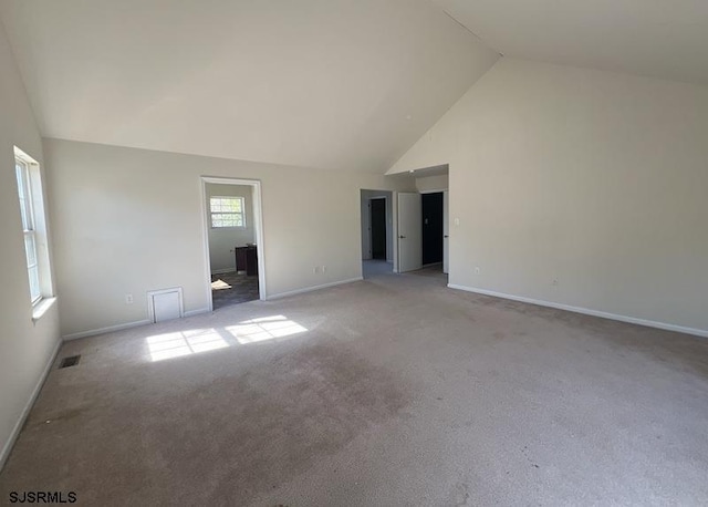 empty room with baseboards, high vaulted ceiling, and light colored carpet