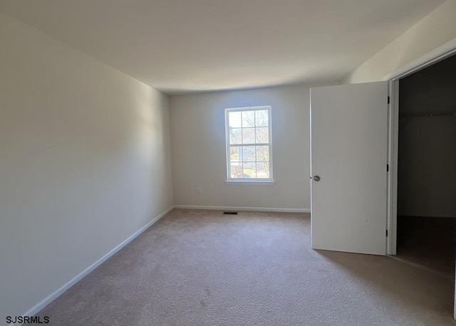 unfurnished room featuring carpet, visible vents, and baseboards