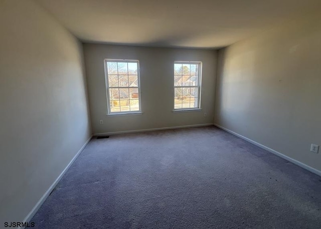 spare room with carpet floors, visible vents, and baseboards