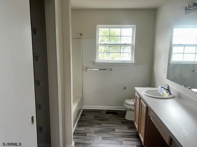 full bathroom with toilet, wood finished floors, bathing tub / shower combination, vanity, and baseboards