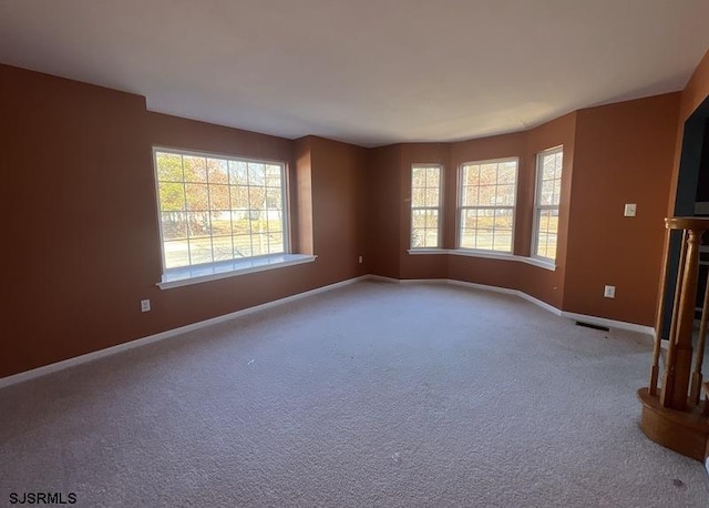 carpeted empty room featuring visible vents and baseboards