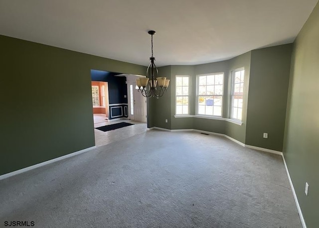 unfurnished dining area with a chandelier, visible vents, carpet floors, and baseboards