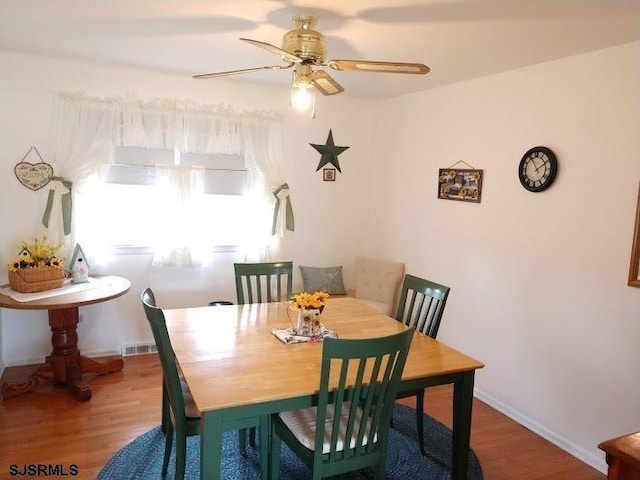 dining area featuring a ceiling fan, wood finished floors, visible vents, and baseboards