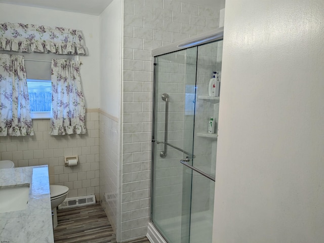 bathroom featuring toilet, a shower stall, visible vents, and tile walls