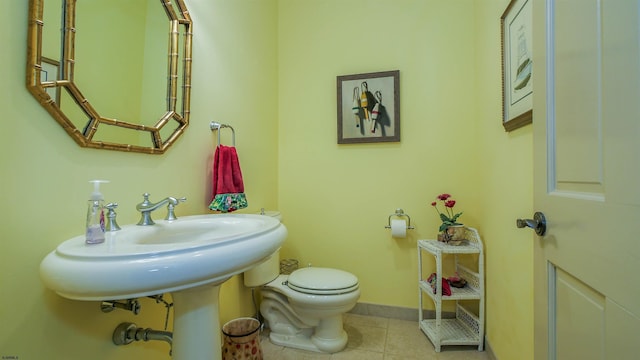 half bathroom featuring tile patterned flooring, baseboards, and toilet