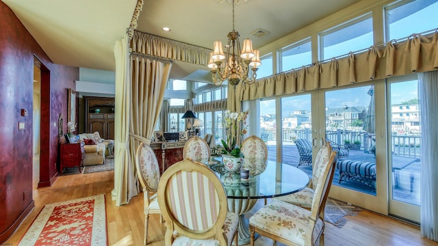 dining space featuring wood finished floors, visible vents, and a notable chandelier