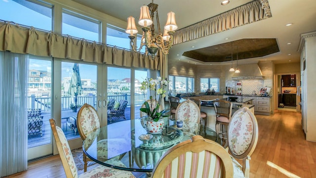 dining space featuring recessed lighting, a raised ceiling, an inviting chandelier, and wood finished floors