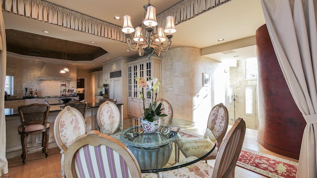 dining area featuring a tray ceiling, light wood-type flooring, recessed lighting, and a notable chandelier