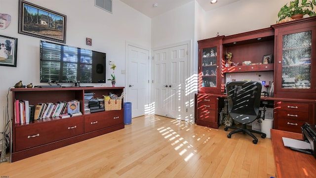 office space with a high ceiling, wood finished floors, and visible vents