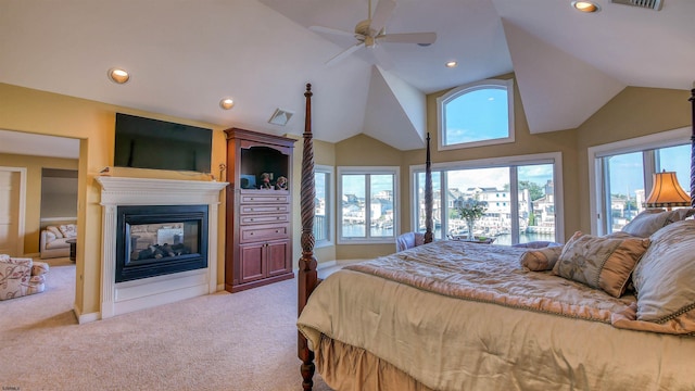 carpeted bedroom with lofted ceiling, multiple windows, visible vents, and a multi sided fireplace