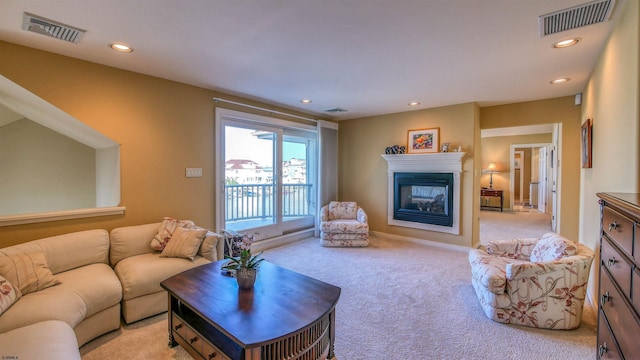 living area featuring light carpet, recessed lighting, visible vents, and a glass covered fireplace