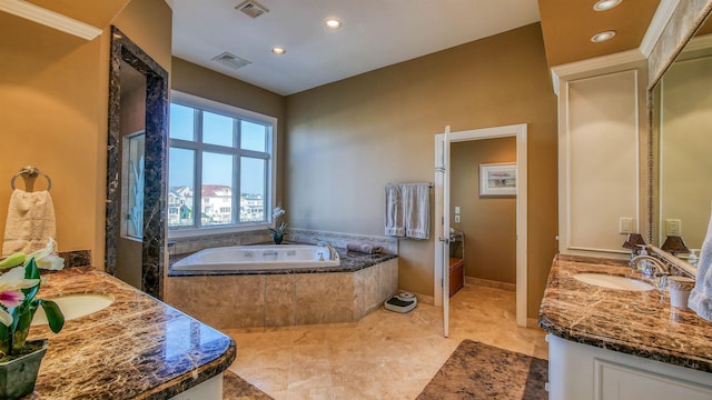 bathroom with a garden tub, visible vents, two vanities, and a sink