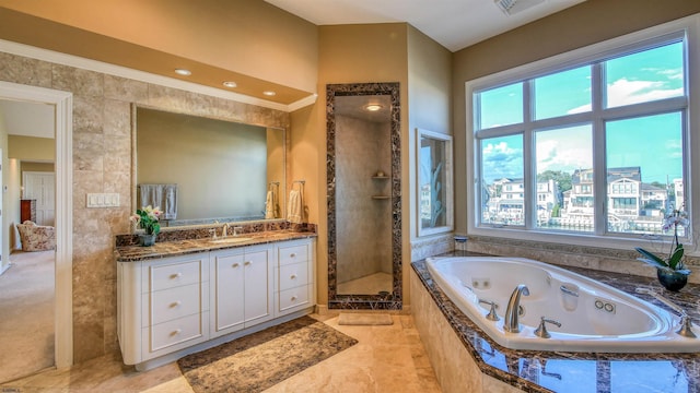 bathroom with a tub with jets, plenty of natural light, a shower stall, and vanity