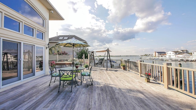 wooden deck with outdoor dining space and a water view