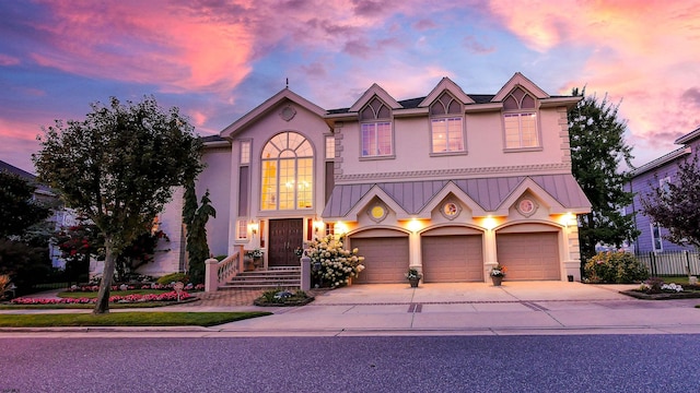 view of front of property featuring metal roof, fence, driveway, stucco siding, and a standing seam roof