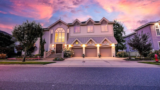 view of front of home featuring concrete driveway, fence, metal roof, and stucco siding