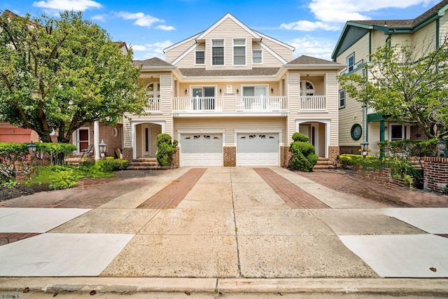 view of front of property with brick siding, driveway, a balcony, and an attached garage