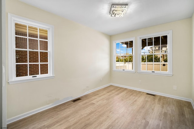 empty room featuring wood finished floors, visible vents, and baseboards