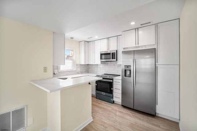 kitchen with light wood finished floors, tasteful backsplash, visible vents, appliances with stainless steel finishes, and a peninsula