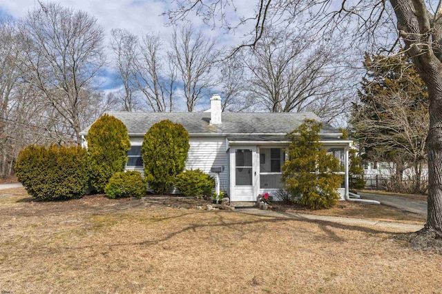 ranch-style home with roof with shingles, a chimney, and a front lawn