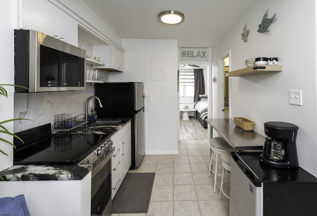 kitchen with open shelves, light tile patterned floors, white cabinets, and stainless steel appliances