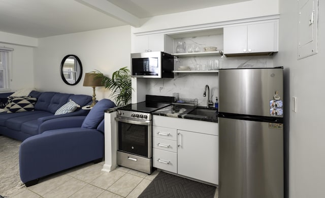 kitchen featuring white cabinets, dark countertops, appliances with stainless steel finishes, open floor plan, and a sink