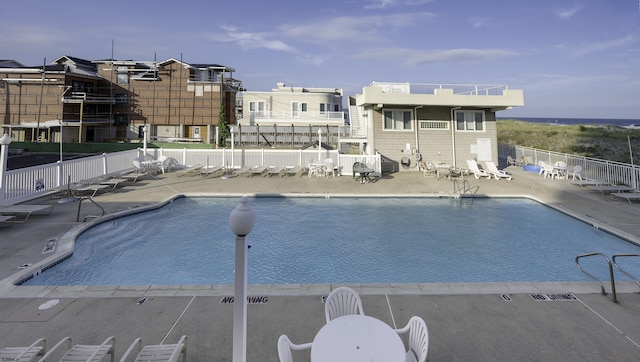 community pool with a patio area and fence