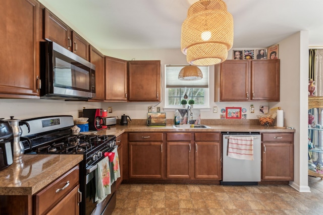 kitchen with brown cabinets, stone finish flooring, stainless steel appliances, and a sink