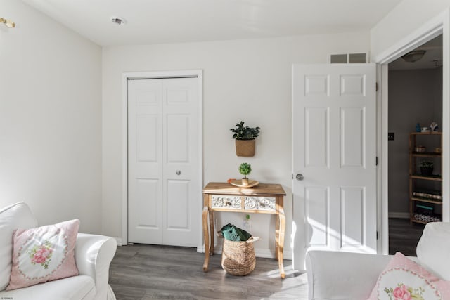 living area with wood finished floors, visible vents, and baseboards