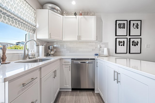 kitchen featuring white cabinets, decorative backsplash, dishwasher, light countertops, and a sink