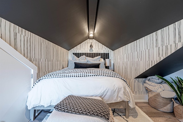 bedroom with lofted ceiling, wallpapered walls, and wood finished floors