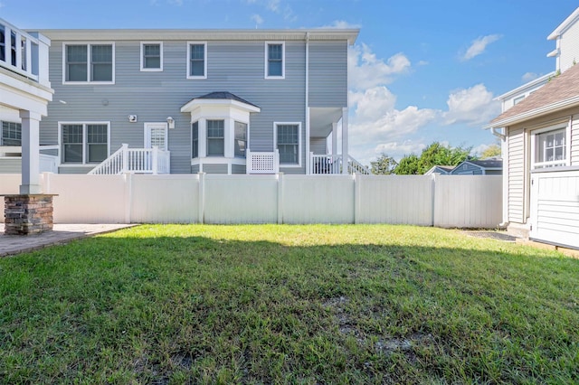 rear view of house with a yard and fence