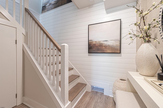 stairway with wood finished floors and wooden walls