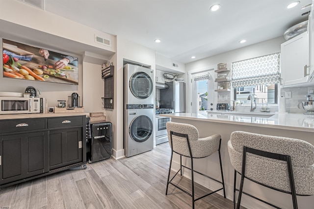 kitchen featuring open shelves, stainless steel appliances, stacked washer / drying machine, light countertops, and visible vents