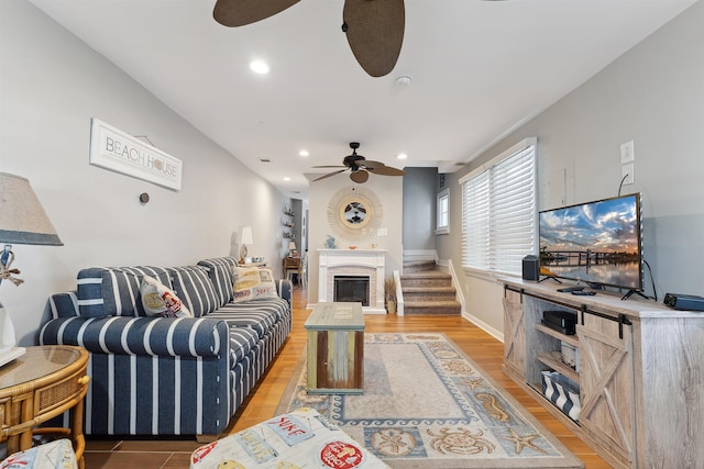 living area with a fireplace, recessed lighting, a ceiling fan, light wood-style floors, and baseboards