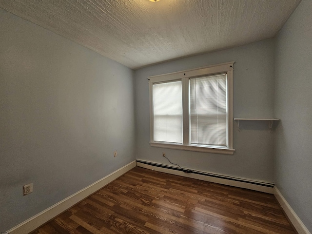 spare room with dark wood-style floors, baseboards, baseboard heating, and a textured ceiling