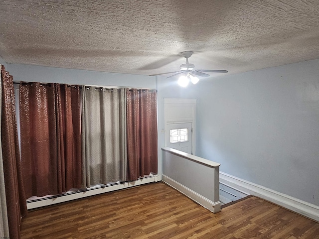 unfurnished room featuring a baseboard heating unit, a ceiling fan, a textured ceiling, wood finished floors, and baseboards