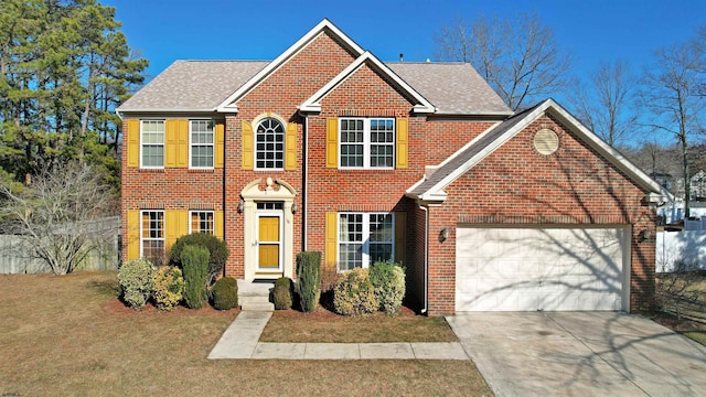 colonial home with a garage, brick siding, concrete driveway, roof with shingles, and a front yard