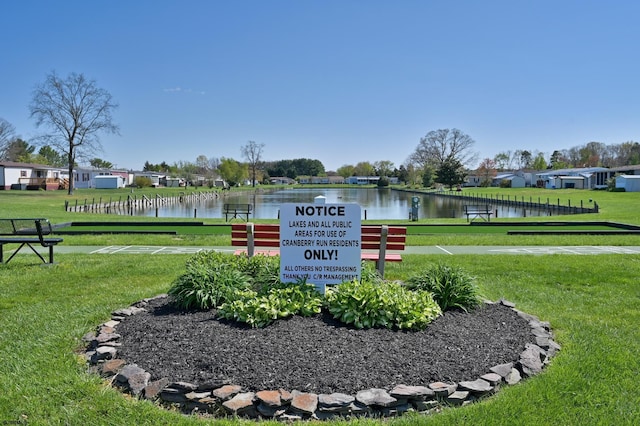 view of home's community with a water view and a yard