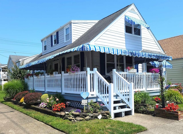 view of front facade with covered porch and a shingled roof