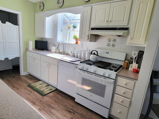 kitchen with tasteful backsplash, dark wood-type flooring, a sink, white appliances, and under cabinet range hood